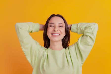 Top above hight angle view photo of young girl hands behind head rest dream sleep relax isolated on yellow color backgroundの写真素材