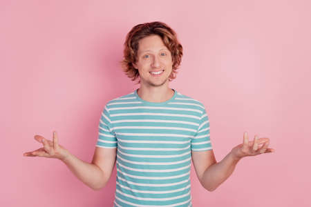 Photo of hospitable guy raise hands wear casual blue striped t-shirt on pink backgroundの写真素材