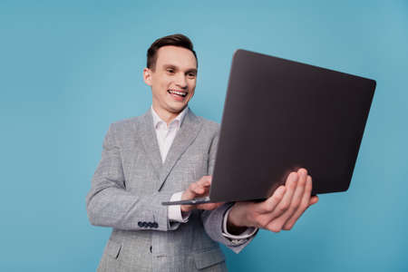 Photo of young business man happy positive smile chat type email project laptop isolated over blue color backgroundの写真素材