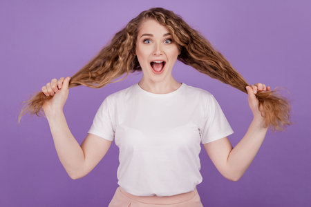 Photo of crazy shocked funky lady hold healthy curly tails wear casual outfit on purple backgroundの写真素材