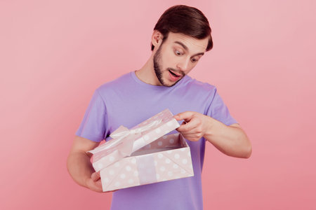 Photo of handsome young man get present gift box curious interested open isolated over pink color...