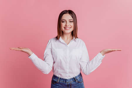Photo of young cheerful girl hold hands product promo proposition ad isolated over pink color backgroundの写真素材