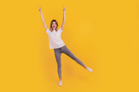 Photo of funky friendly lady dance show v-sign raise hands wear casual t-shirt jeans sneakers on...