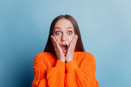 Photo of young girl amazed shocked fake news hands touch cheeks crazy isolated over blue color backgroundの写真素材