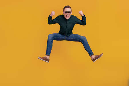 Full body photo of young excited man rejoice victory win lottery jump up isolated over yellow color backgroundの写真素材