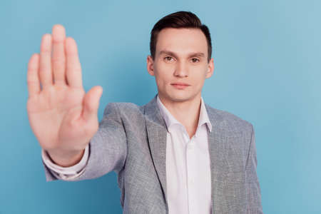 Photo of young man hold hand show no stop decline denial forbidden rules sign isolated over blue color backgroundの写真素材