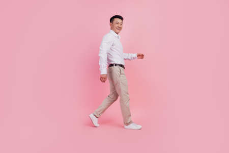 Full body profile side photo of young asian man good mood go walk isolated over pink color backgroundの写真素材