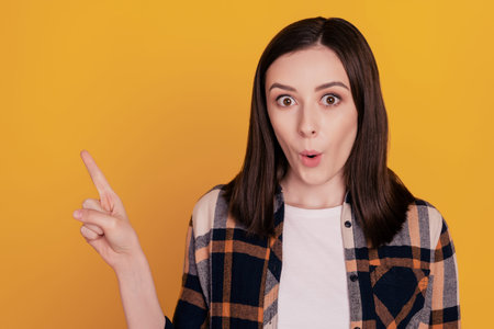 Photo of shocked crazy positive lady indicate finger empty space isolated yellow color backgroundの写真素材