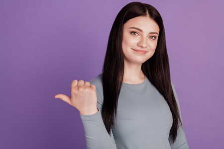 Photo of young girl point thumb empty space ad promo choose suggest isolated over violet color...