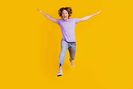 Photo of crazy inspired energetic active man jump wear casual jeans clothes on yellow backgroundの写真素材