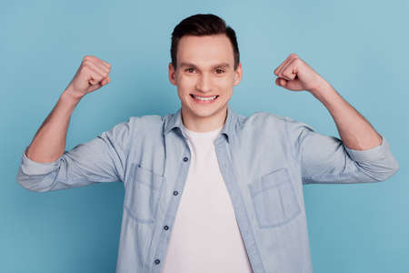 Photo of young man happy positive smile celebrate win victory muscles sporty isolated over blue color backgroundの写真素材