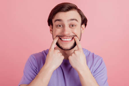 Close up portrait of positive guy happy positive indicate fingers toothy smile oral care isolated on pink color backgroundの写真素材