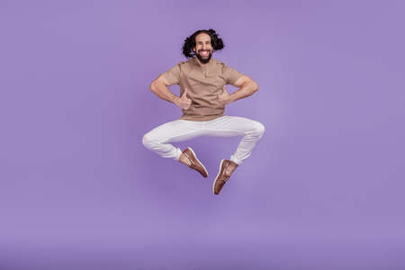 Full body photo of young excited man have fun jump show thumbs-up great suggest isolated on purple color backgroundの写真素材
