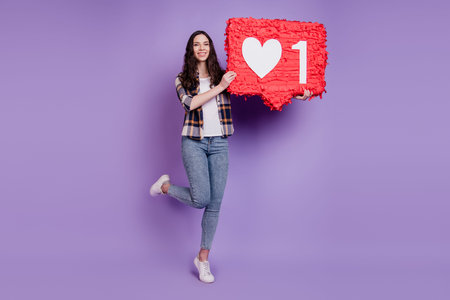 Photo of young girl hold paper pinata heart like reaction icon popular isolated over purple color...