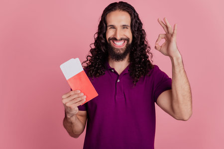 Photo of reliable promoter man hold low-cost tickets show okey sign wear purple t-shirt isolated on...