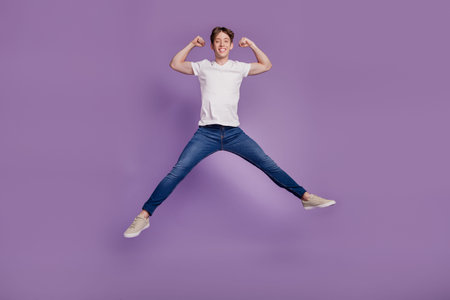 Full body photo of young man jump up show hands muscles bodycare sportive isolated on violet color...