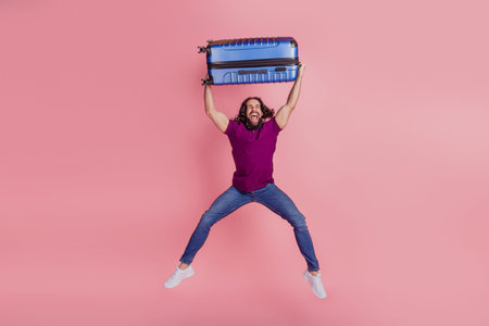 Full size photo of young excited latin man have fun hold baggage jumper tourist isolated on pink...