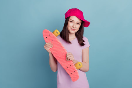 Photo of funny cute young lady wear hat holding longboard skater sporty isolated turquoise color...