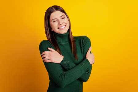 Photo of adorable lady receive comfy self-cuddle wear green shirt isolated on yellow backgroundの写真素材
