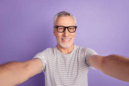 Photo of cheerful senior man record video shoot selfie vacation travel isolated over violet color backgroundの写真素材