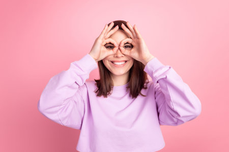 Photo of youth lovely girl good mood show fingers binoculars eyeglasses isolated over pink color backgroundの写真素材