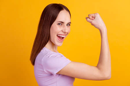 Profile side photo of young excited lady show hand muscles rejoice success sportive isolated over yellow color backgroundの写真素材