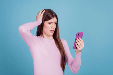 Photo of excited girl amazed shocked surprised look read fake news cellphone isolated over blue color backgroundの写真素材