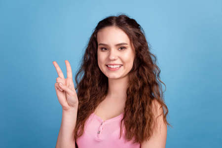 Photo of young charming excited woman show fingers peace cool v-symbol isolated over blue color backgroundの写真素材