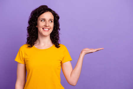 Photo of young cheerful lady curious look empty space offer ads present isolated over violet color backgroundの写真素材