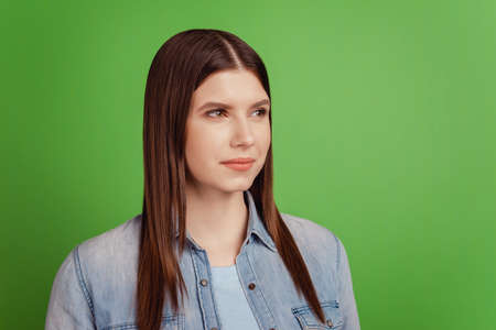 Profile side photo of young pretty woman thoughtful look empty space isolated over green color backgroundの写真素材