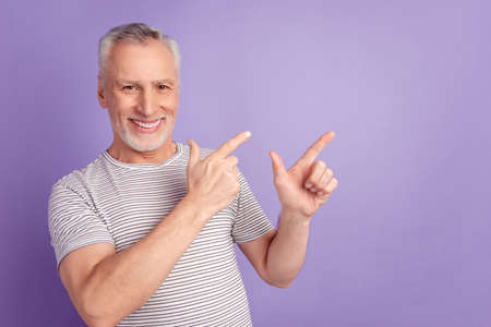 Photo of senior man indicate fingers empty space promotion advert isolated over violet color backgroundの写真素材