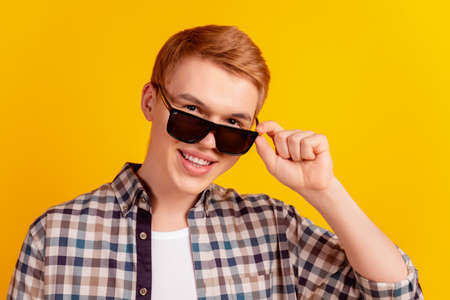 Photo of young cheerful guy hand touch eyeglasses cool ginger hair isolated over yellow color backgroundの写真素材