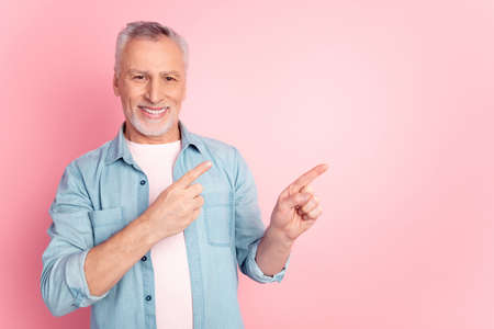 Photo of mature man indicate fingers empty space advertise choose subscribe isolated over pink color backgroundの写真素材