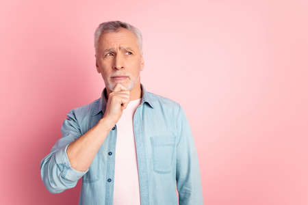 Photo of senior man arm touch chin wondered look empty space consider isolated over pink color backgroundの写真素材