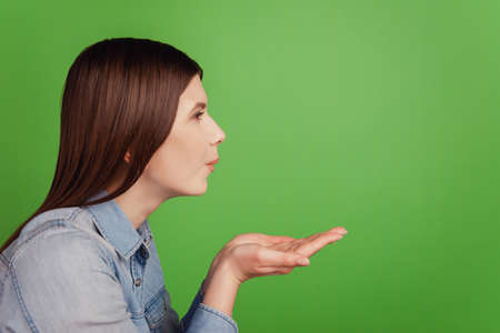 Profile side photo of young attractive girl pouted lips send air kiss isolated over green color backgroundの写真素材