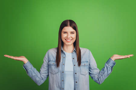 Photo of young attractive woman hold hands proposition advertise decision isolated over green color backgroundの写真素材