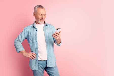 Photo of aged man look cellphone post repost coment social network isolated over pink color backgroundの写真素材