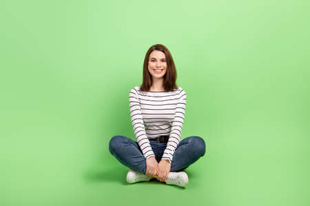 Full size photo of young lovely girl sitting floor rest dream wear casual clothes isolated over green color backgroundの写真素材
