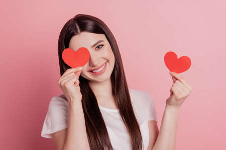 Portrait of attractive lovely cheerful girl happy positive smile small little heart romantic isolated over pink backgroundの写真素材
