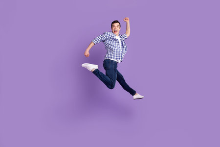 Full size profile side photo of young excited man go walk run jump up air isolated over purple color...