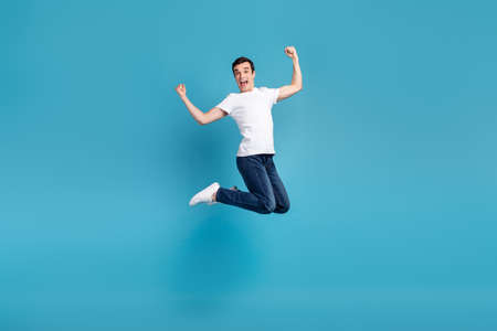 Full body photo of young excited man have fun jumper rejoice victory success isolated over blue color backgroundの写真素材