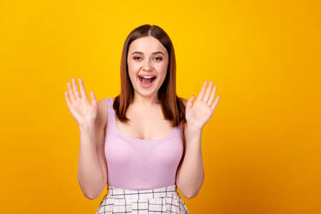 Photo of young cheerful lady excited waving hands hello symbol isolated over yellow color backgroundの写真素材