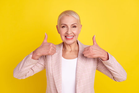 Photo of mature woman show fingers thumb-up advert suggest quality isolated over yellow color...