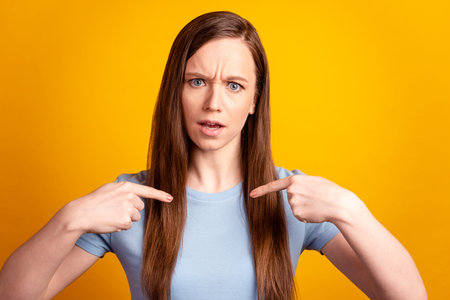 Photo of young woman indicate fingers herself misunderstanding puzzled isolated over yellow color...