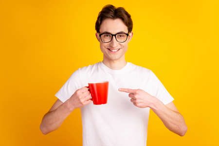Photo of young guy indicate finger mug advertise choice promo espresso isolated over yellow color backgroundの写真素材