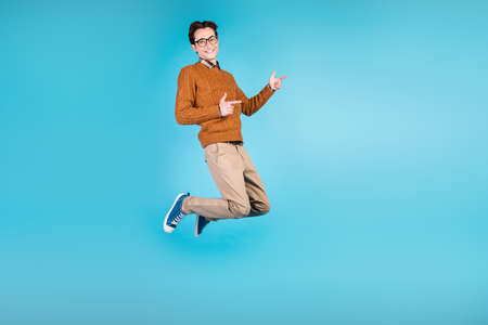 Full size profile side photo of young man indicate fingers empty space promo ads isolated over blue color backgroundの写真素材