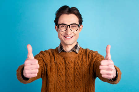 Photo of young cheerful guy show thumbs-up approve good advertise ideal isolated over blue color backgroundの写真素材