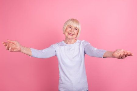 Photo of lovely aged woman open arms welcome hospitable friendly cuddle isolated over pink color...