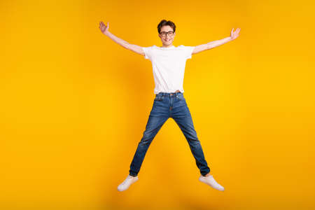 Full length photo of young guy good mood jump up wear casual clothes isolated over yellow color backgroundの写真素材