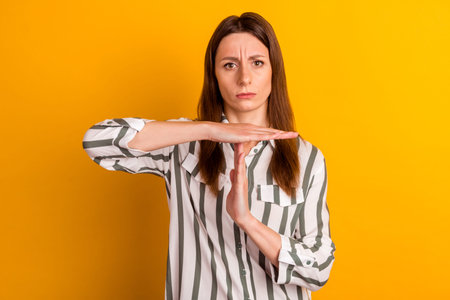 Photo of mature pretty woman show hands time-out symbol referee stop isolated over yellow color...